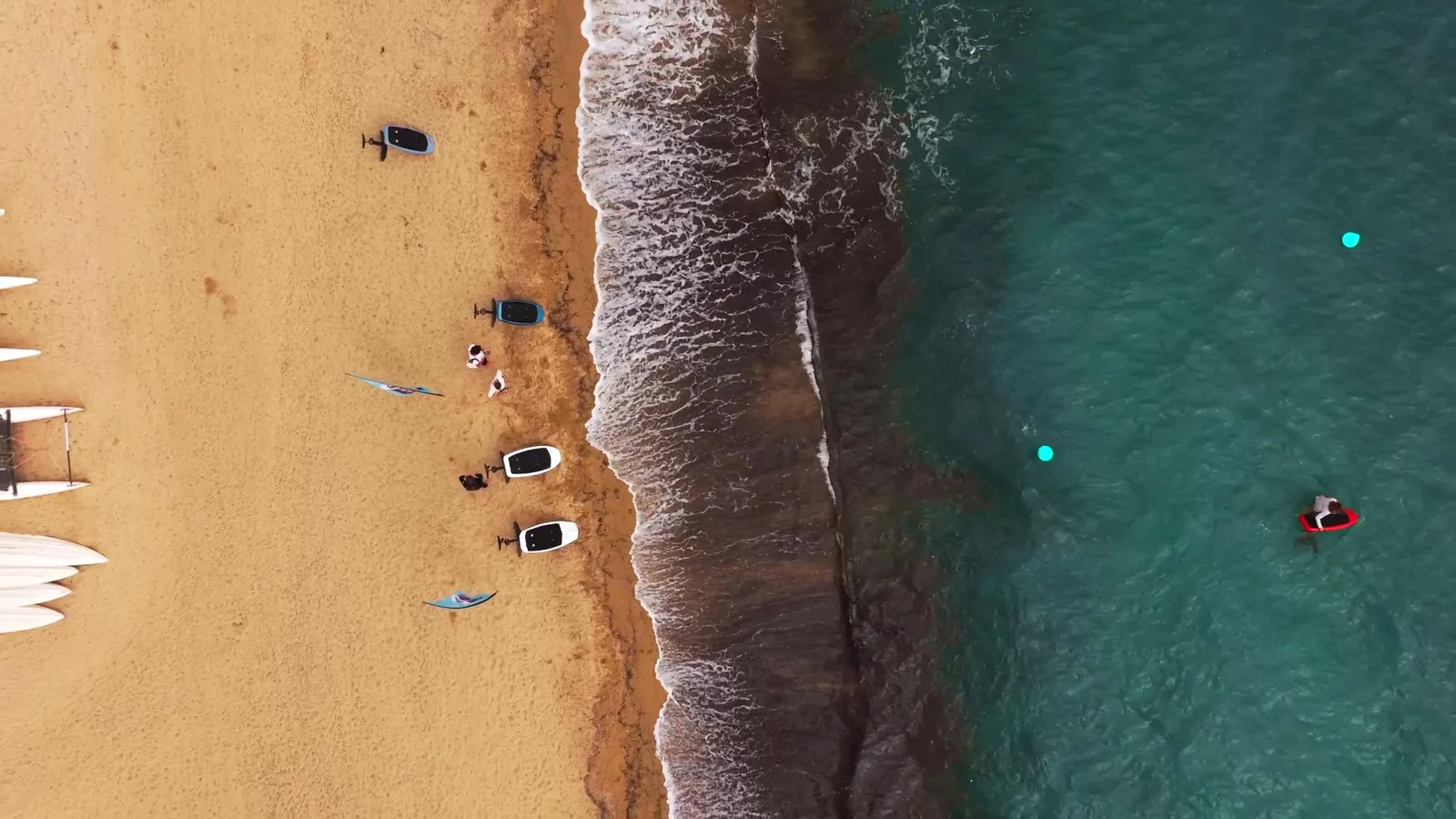 Vue aérienne d'une crique sauvage bordée de pins, eau turquoise et roche du littoral.