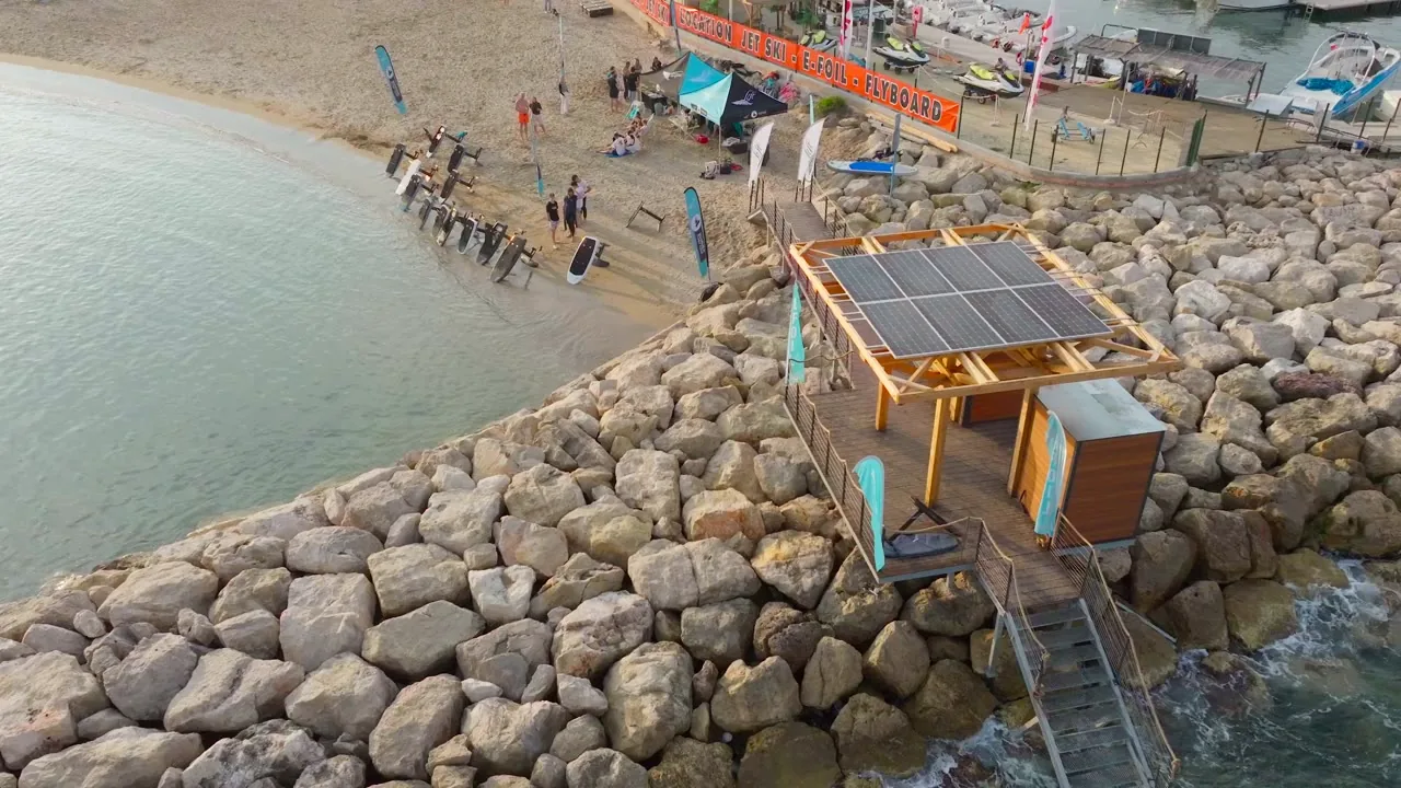 Vue aérienne du littoral préservé : criques et pins au bord d'une eau claire.